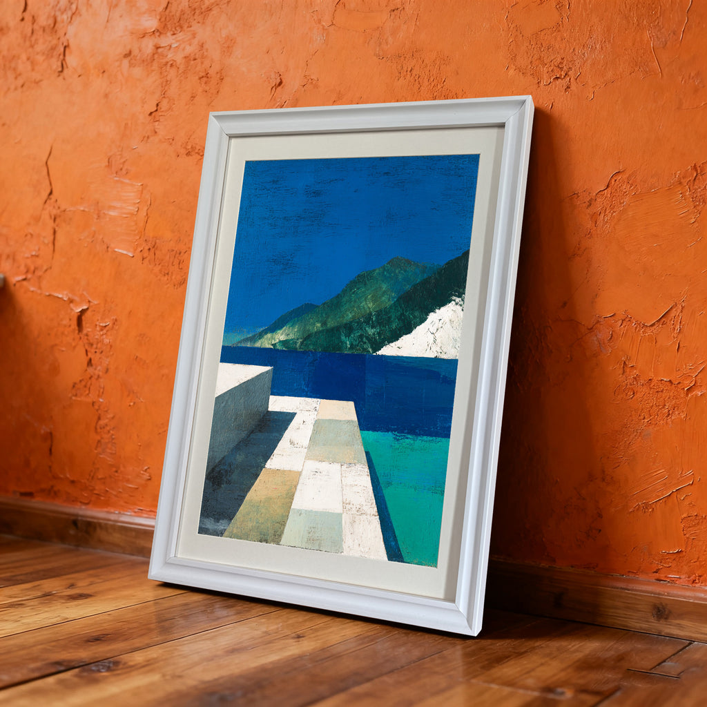 White-framed abstract landscape art print leaning on the floor against a vivid, textured orange wall.