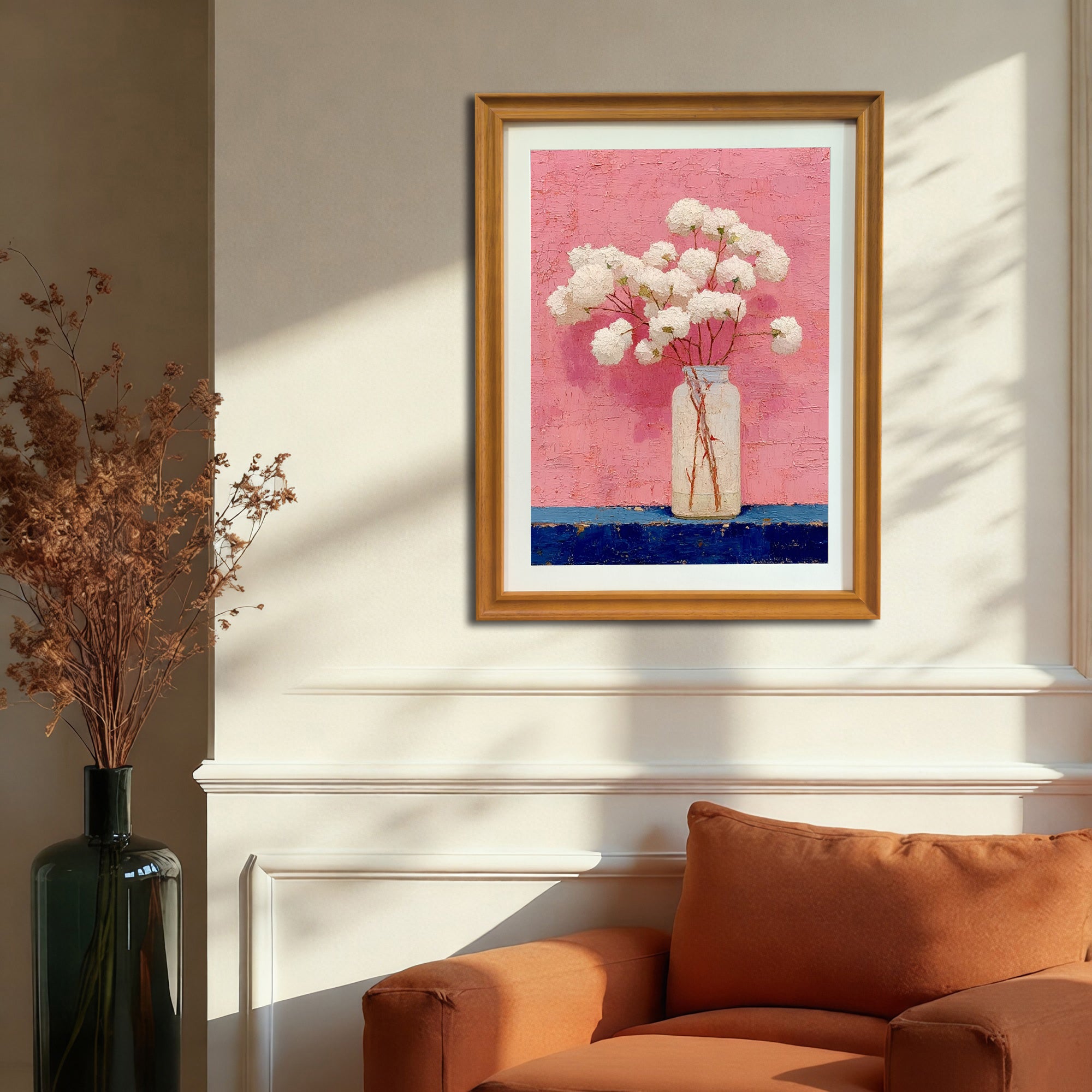 The art print, in a natural wood/gold frame, hangs on a cream-colored wall above an orange armchair in a sunlit room, showcasing the artwork's scale in a cozy home setting.