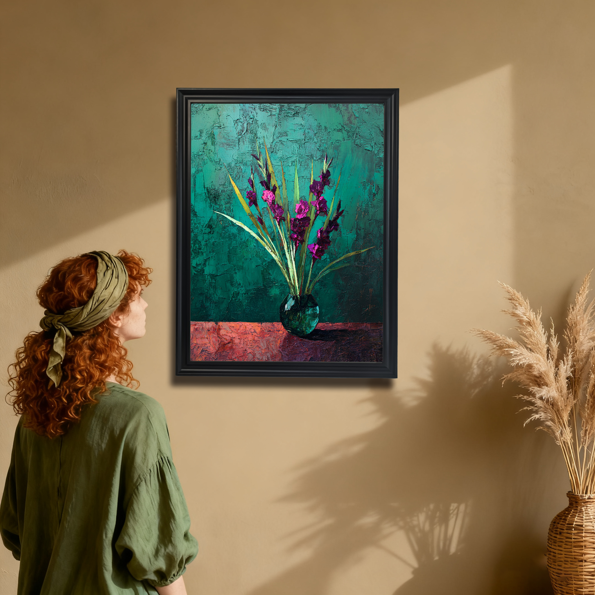 Woman with red hair looking at a black-framed art print of textured purple flowers in a vase, hanging on a warm beige wall with a wicker vase nearby.