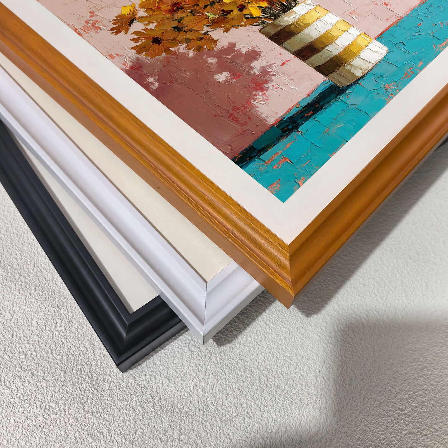 Close-up of stacked black, white, and natural wood picture frames showcasing thick impasto paint texture on canvas.