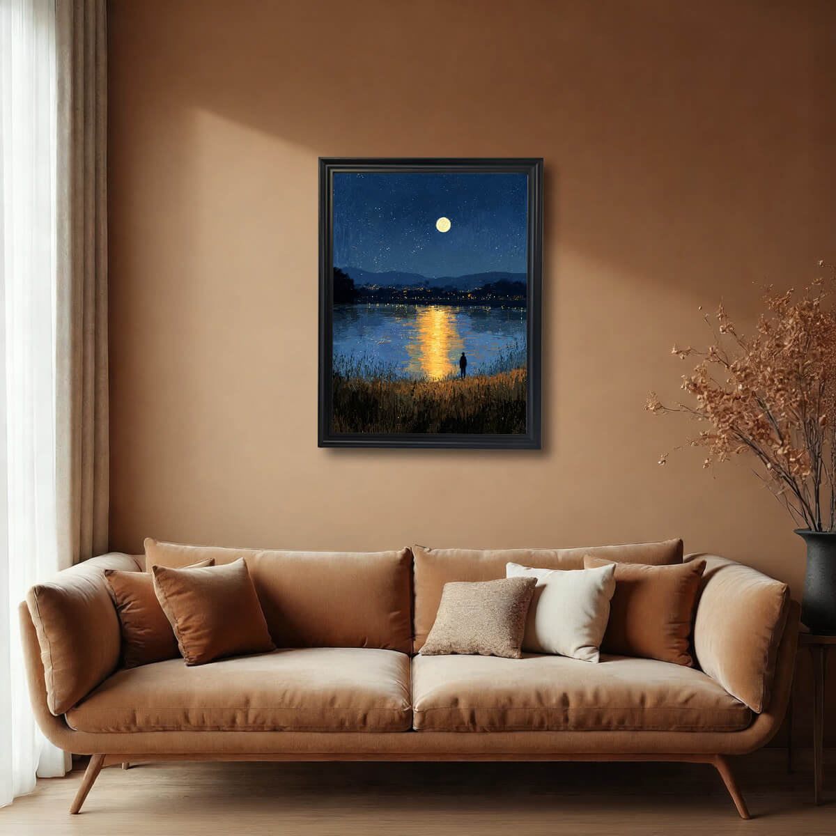 A framed art print of a dramatic moonlit lake and starry sky, with a yellow reflection strip down the middle. The print is in a black frame, hanging above a tan velvet sofa in a room with warm, earthy brown walls.