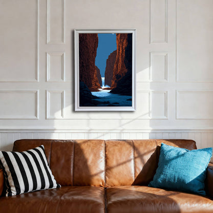 A framed art print of a canyon waterfall under a starry sky, hanging on a white wainscoted wall above a brown leather sofa. The frame is white.