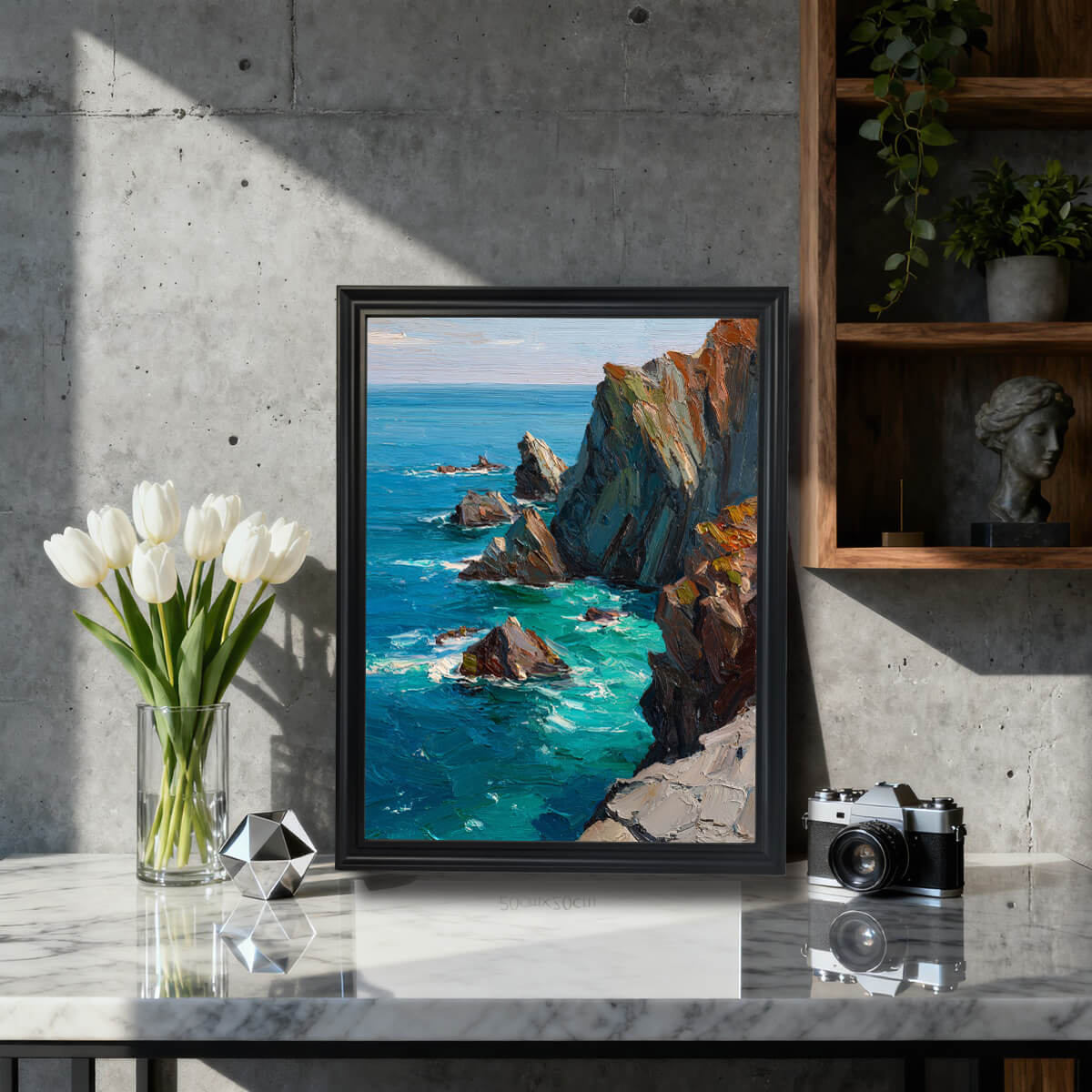 The impressionist seascape art print framed in black, standing on a marble countertop next to a vase of white tulips and a vintage camera, against a modern concrete wall backdrop.