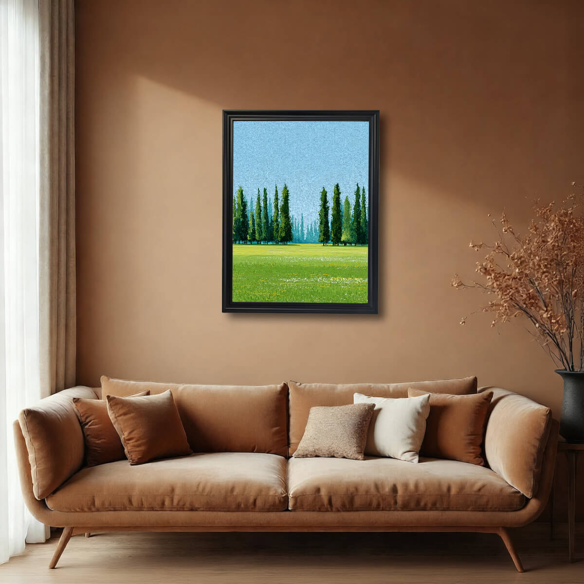 A framed art print of a green meadow and Cypress trees, hanging above a tan velvet sofa in a room with warm, earthy brown walls. The frame is black.