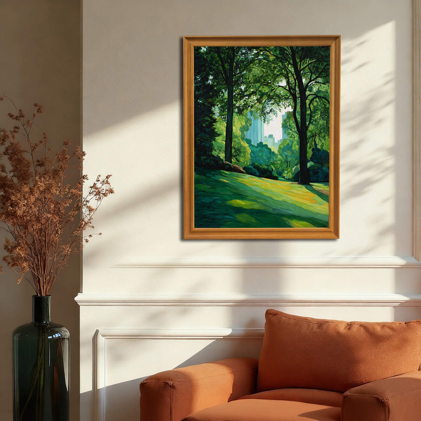 City park and skyline art print in a gold or dark natural wood frame hanging above an orange armchair and white wainscoting, illustrating a warm, classic living room decor.