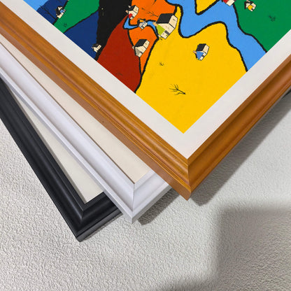 A corner close-up showing the detail of the color-block village art print and three stacked frame options: warm wood, white, and black, demonstrating the available wood frame styles with a white mat.