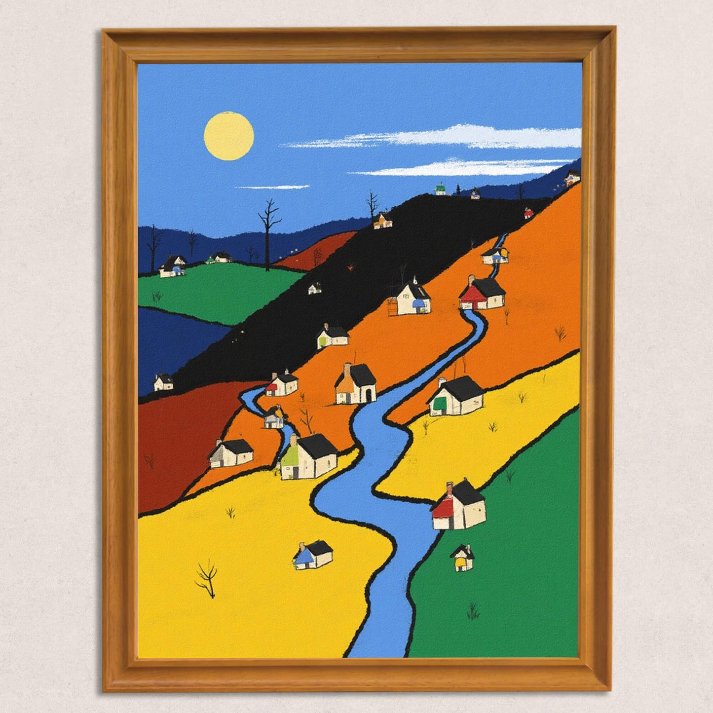 A modern, folk-style art print of a village with small white houses, a winding blue river, and hills in contrasting color blocks (yellow, orange, green, and dark blue), framed in warm wooden trim against a neutral wall.