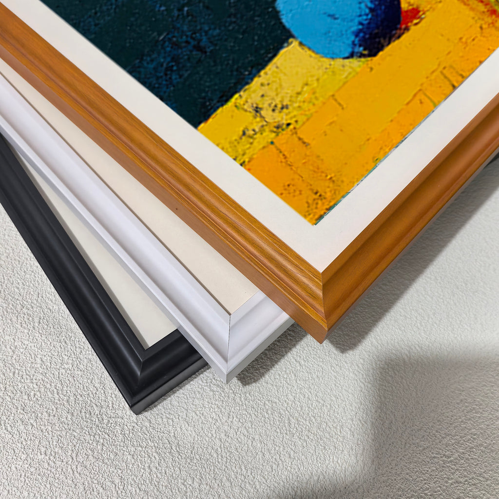 Close-up view of three different wood picture frame corner styles: black, white, and a light brown/natural wood finish, stacked to show the edges.