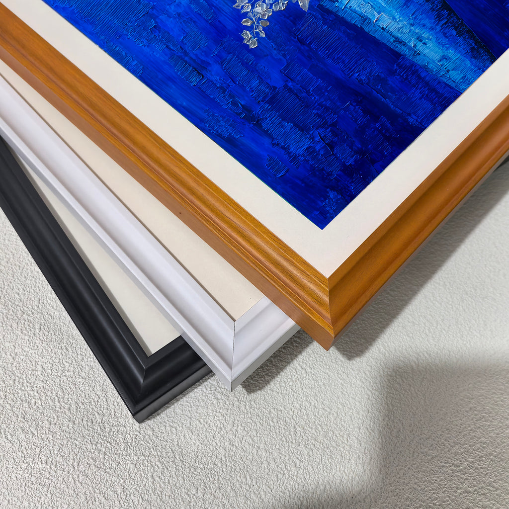 A close-up, stacked view of the corners of four three wooden picture frames: black, white, and light brown (wood grain), showing the frame profiles."