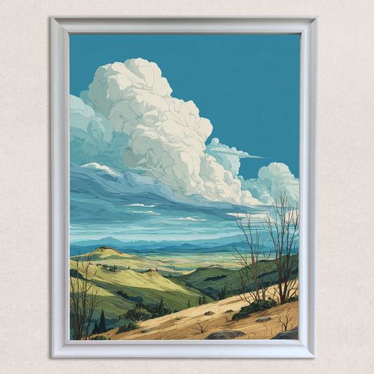 Close-up studio shot of the stylized landscape art print, featuring rolling green and brown hills under a vast blue sky dominated by large, white cumulus clouds, framed in a thick white wood frame.