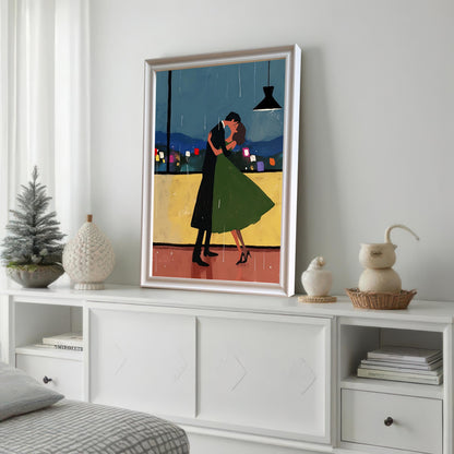 A framed wall art print with a white frame is leaning against a white wall on a white cabinet. The painting depicts a couple dancing in the rain with a city view in the background. The cabinet is decorated with various white decorative objects.