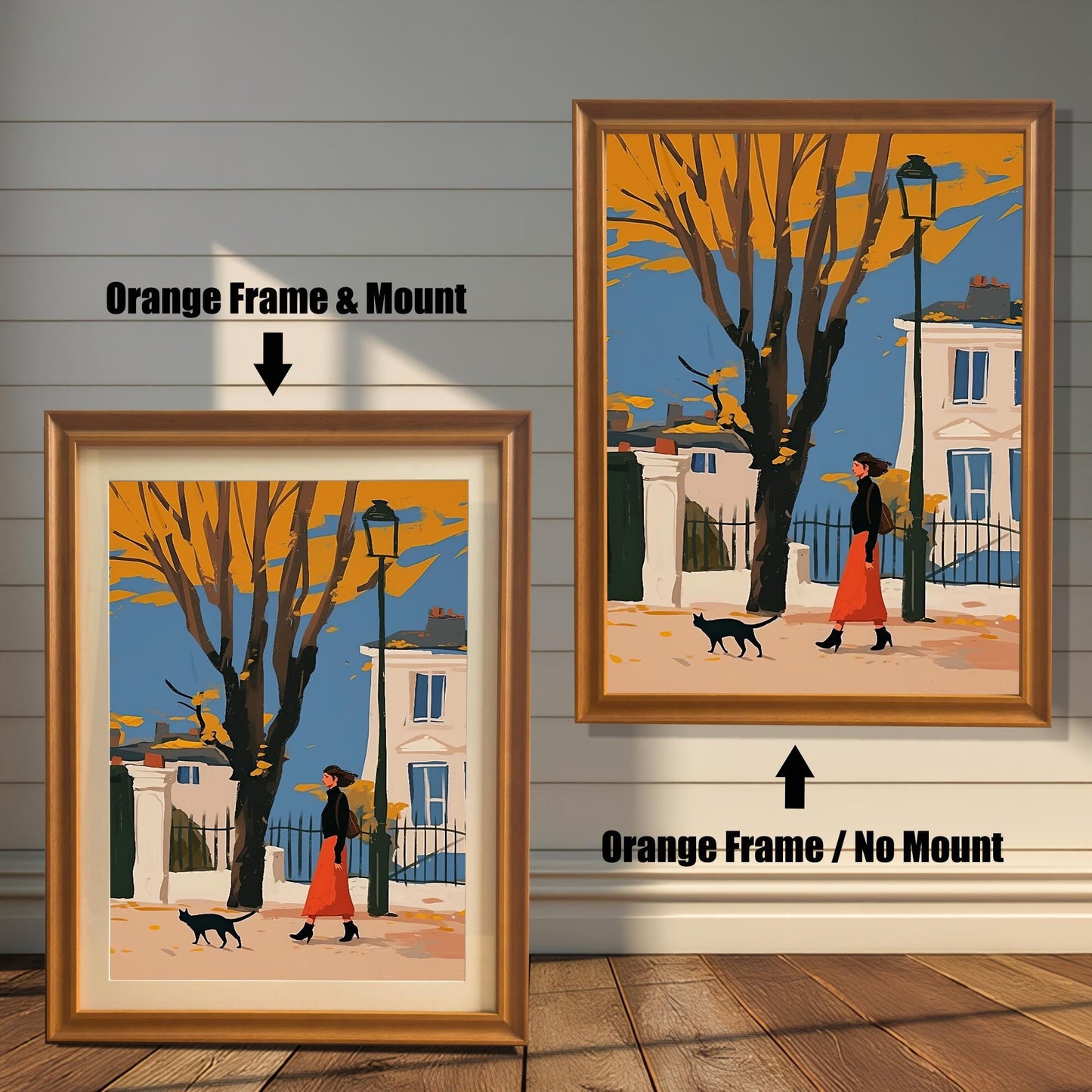 Two framed art prints of a woman and a black cat on an autumn street. The left print has an orange-colored frame and a white mat ("mount"), while the right print has an orange-colored frame with no mat.