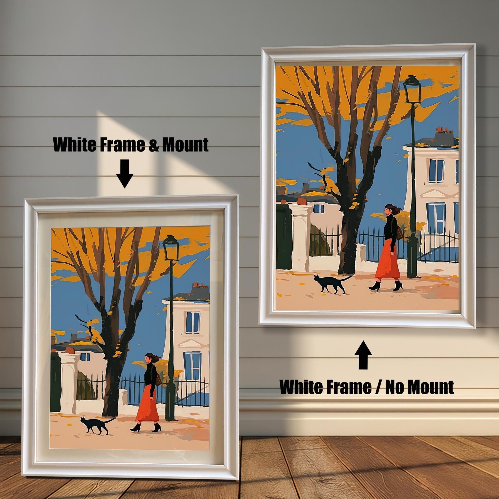 Two framed art prints of a woman and a black cat on a street. The left print has a white frame and a white mat ("mount"), while the right print has a white frame with no mat.