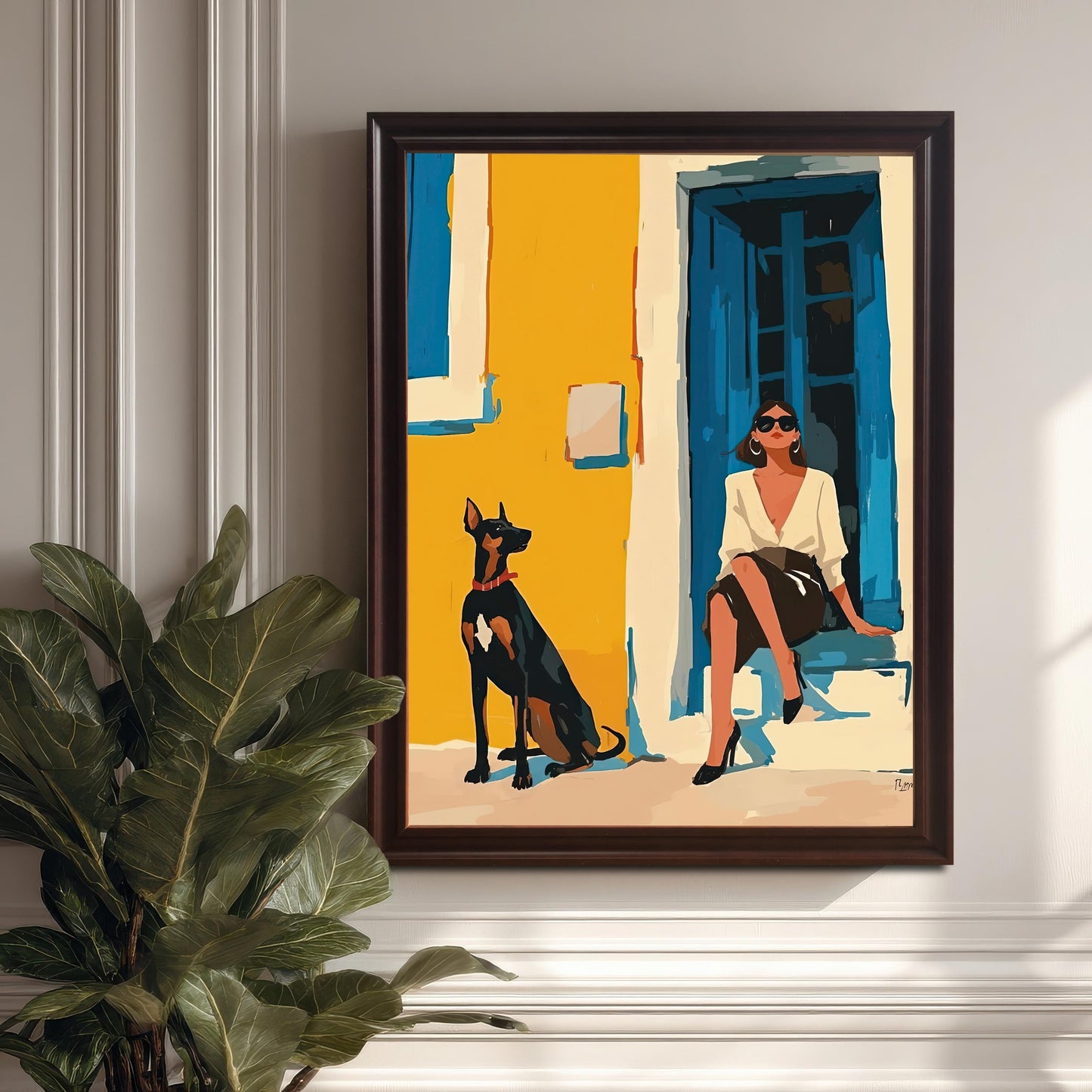 A framed piece of wall art hangs on a white paneled wall. The art depicts a woman in a white shirt and black skirt sitting on a step next to a Doberman Pinscher dog. The frame is a dark coffee brown. A large potted plant sits on the floor to the left of the frame.