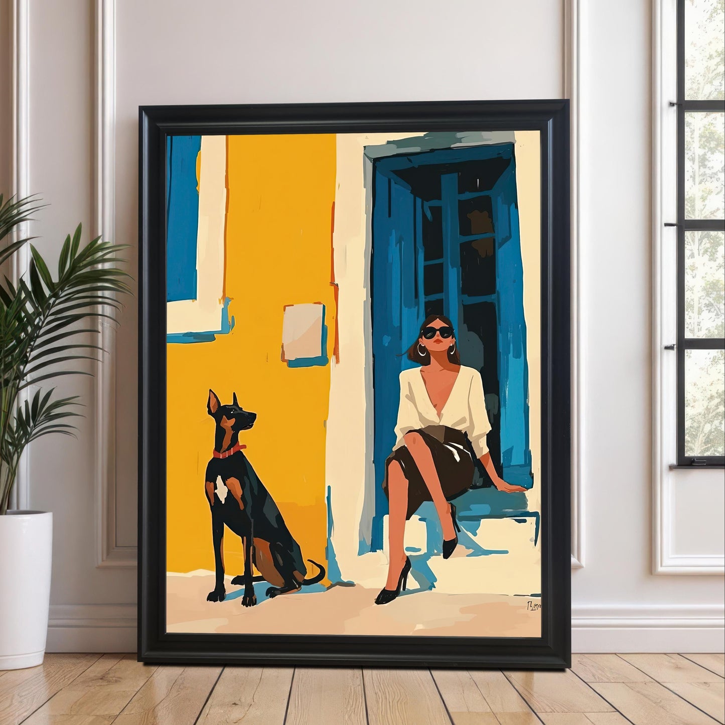 A framed art print with a black frame and a white mat leans against a white paneled wall and rests on a light-colored wooden floor. The art depicts a woman in a white shirt and black skirt sitting on a step next to a Doberman Pinscher dog. A potted plant sits on the floor to the left of the frame.