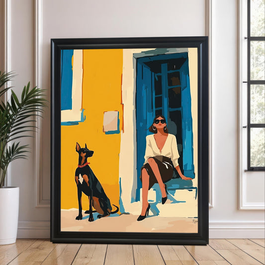 A framed art print with a black frame and a white mat leans against a white paneled wall and rests on a light-colored wooden floor. The art depicts a woman in a white shirt and black skirt sitting on a step next to a Doberman Pinscher dog. A potted plant sits on the floor to the left of the frame.