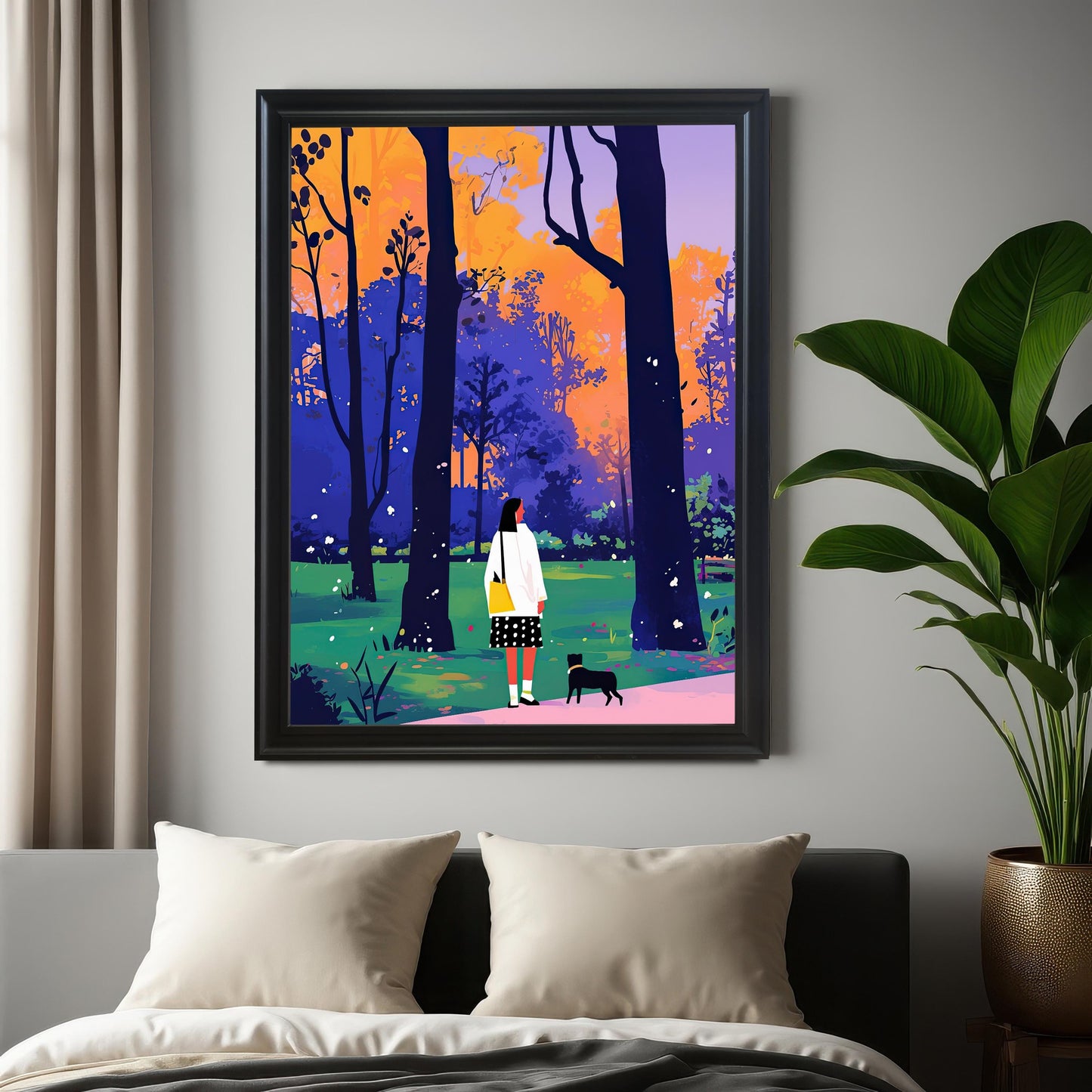 A framed piece of wall art hangs on a gray wall above a bed. The art depicts a woman and a small black dog walking through a park with colorful trees. The frame is black. A large potted plant sits on the floor to the right of the frame.