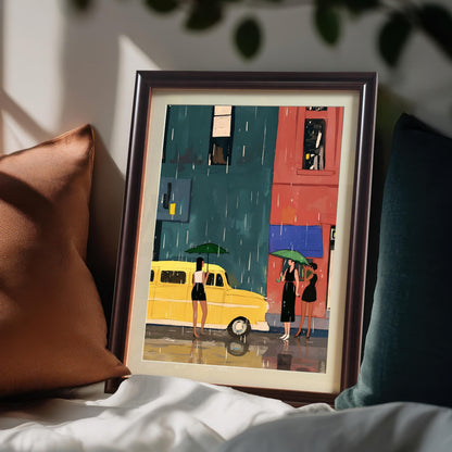 A framed art print with a coffee brown frame and a white mat leans on a bed between two pillows, one brown and one teal. The art depicts a street scene with a yellow bus and three women with umbrellas in the rain.
