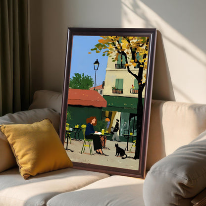 A framed artwork in a coffee-colored frame is propped up on a couch among pillows. The artwork depicts a woman sitting at an outdoor cafe table with a black cat nearby. The background features a building with a red awning and a tree with yellow autumn leaves. The room has a cozy feel with soft lighting.