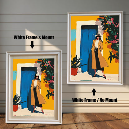 A framed art print is shown in two styles. On the left, a woman in a tan coat stands in front of a yellow wall with a blue door. This print is in a white frame with a white mount (matting). On the right, the same print is shown in a white frame without a mount.