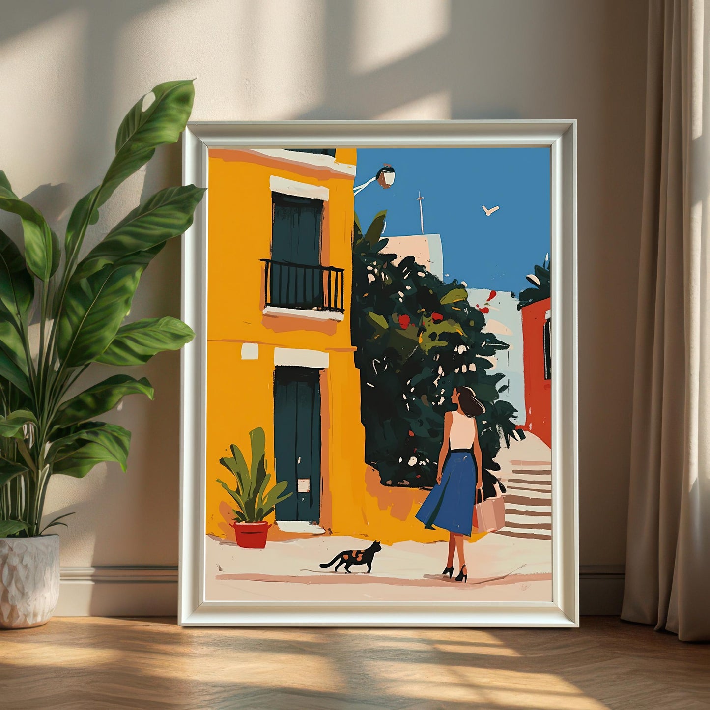 White framed art print of a woman and a cat in a vibrant alley, leaning on a wall next to a potted plant. The white frame complements the artwork's bright yellow and blue tones.