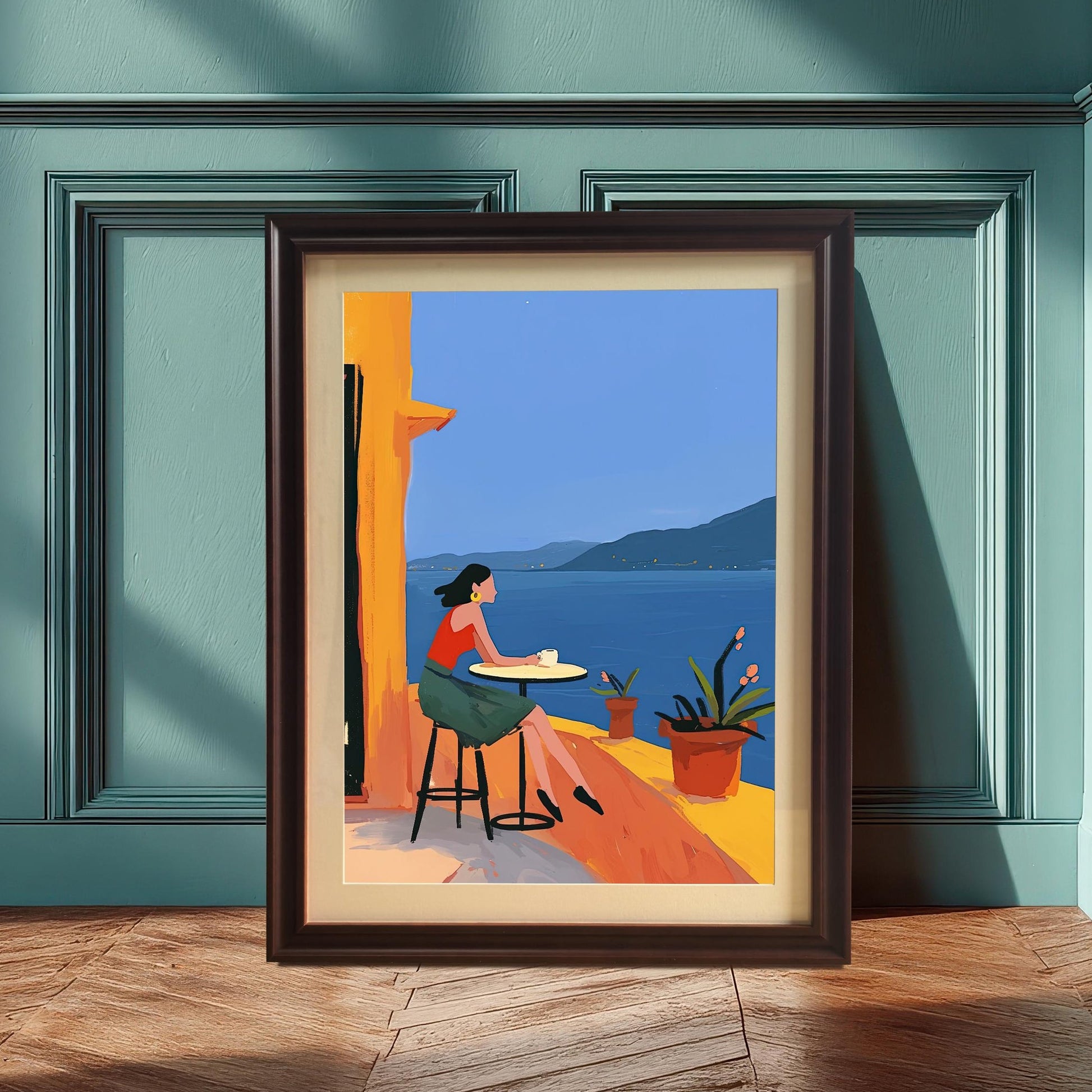 Black framed art print of a woman on a balcony overlooking the ocean. The framed print is leaning against a teal-colored wall, creating a serene and sophisticated feel.