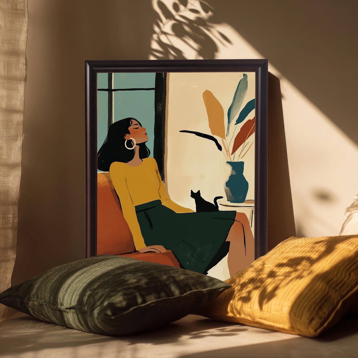 A framed art print of a woman and cat, with a black wood frame, propped on a bench with throw pillows. Sunlight casts shadows from a window across the art.