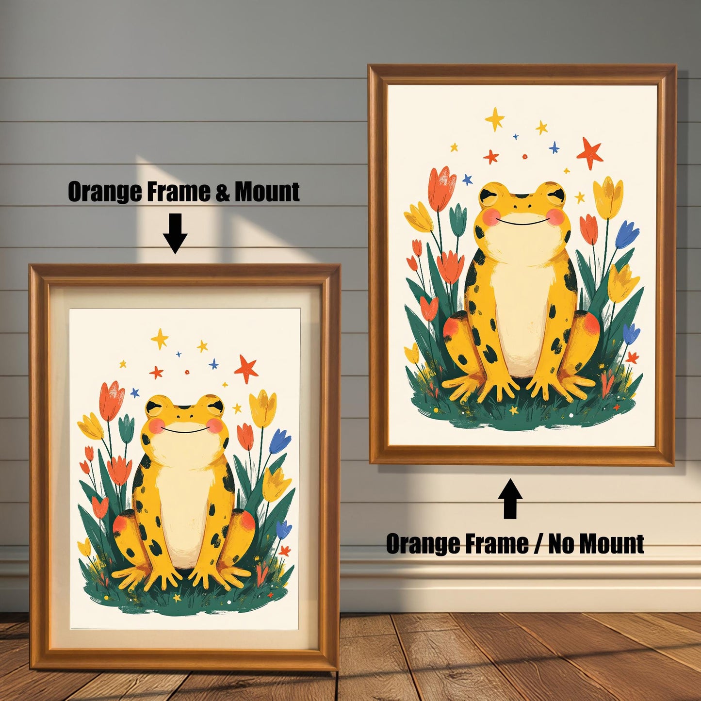 Two versions of a happy yellow frog wall art print with an orange frame. The print on the left is a smaller size framed with a white mount (or mat), and the one on the right is a larger size without a mount. The image shows the framed print hanging against a white paneled wall.