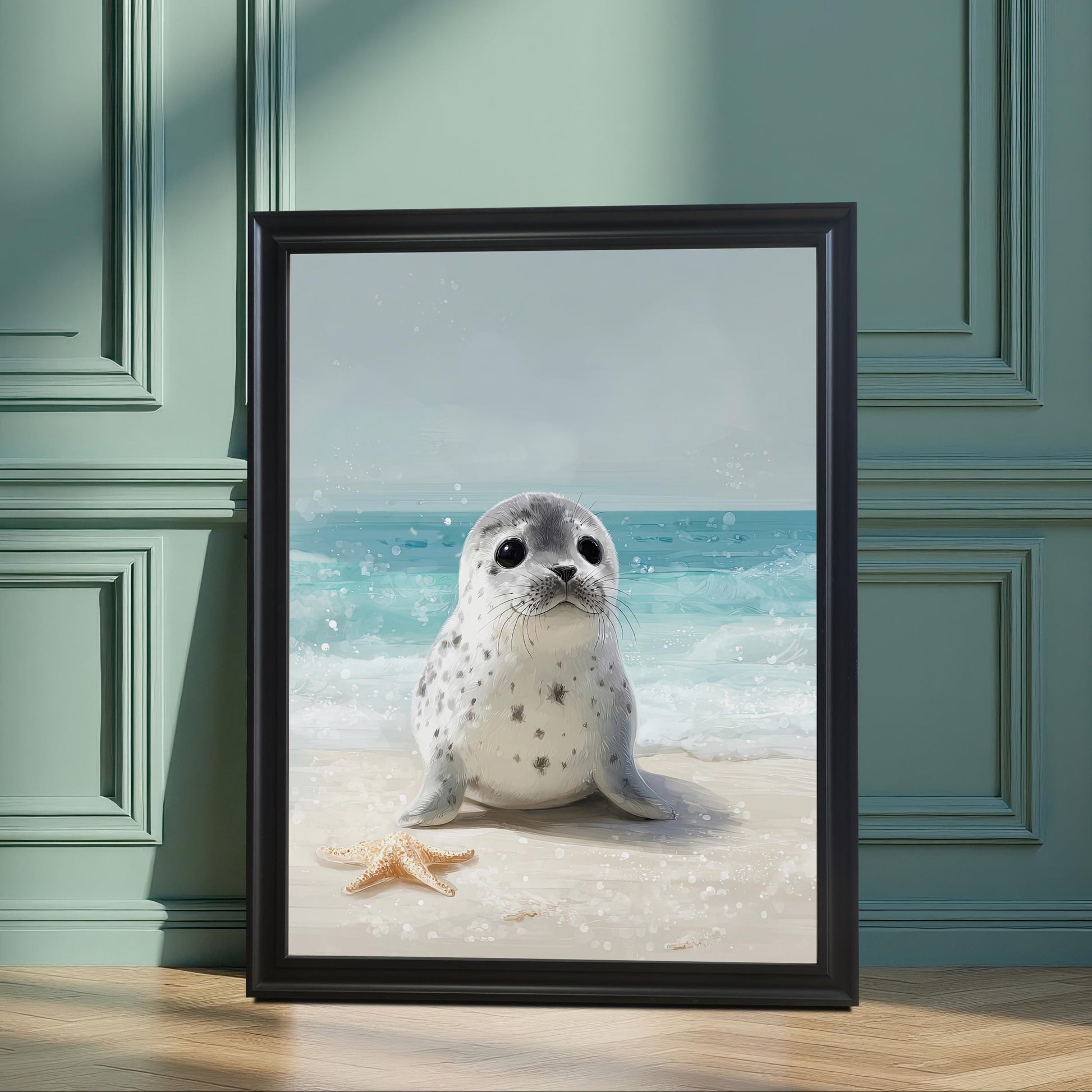 A framed art print of a cute baby seal on a beach, in a black frame. The print is propped on a wooden floor against a paneled teal-green wall, creating a serene, stylish feel.