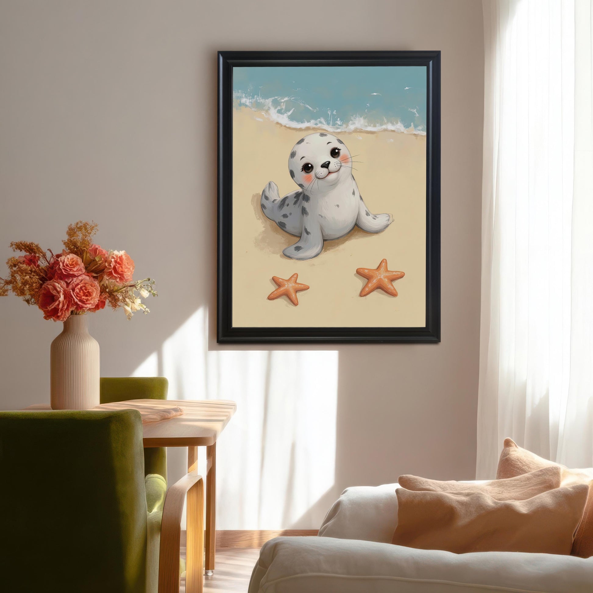 A framed print of a smiling baby seal on a beach is hanging on a light-colored wall. A vase of pink and orange flowers sits on a table next to a green chair in the foreground.