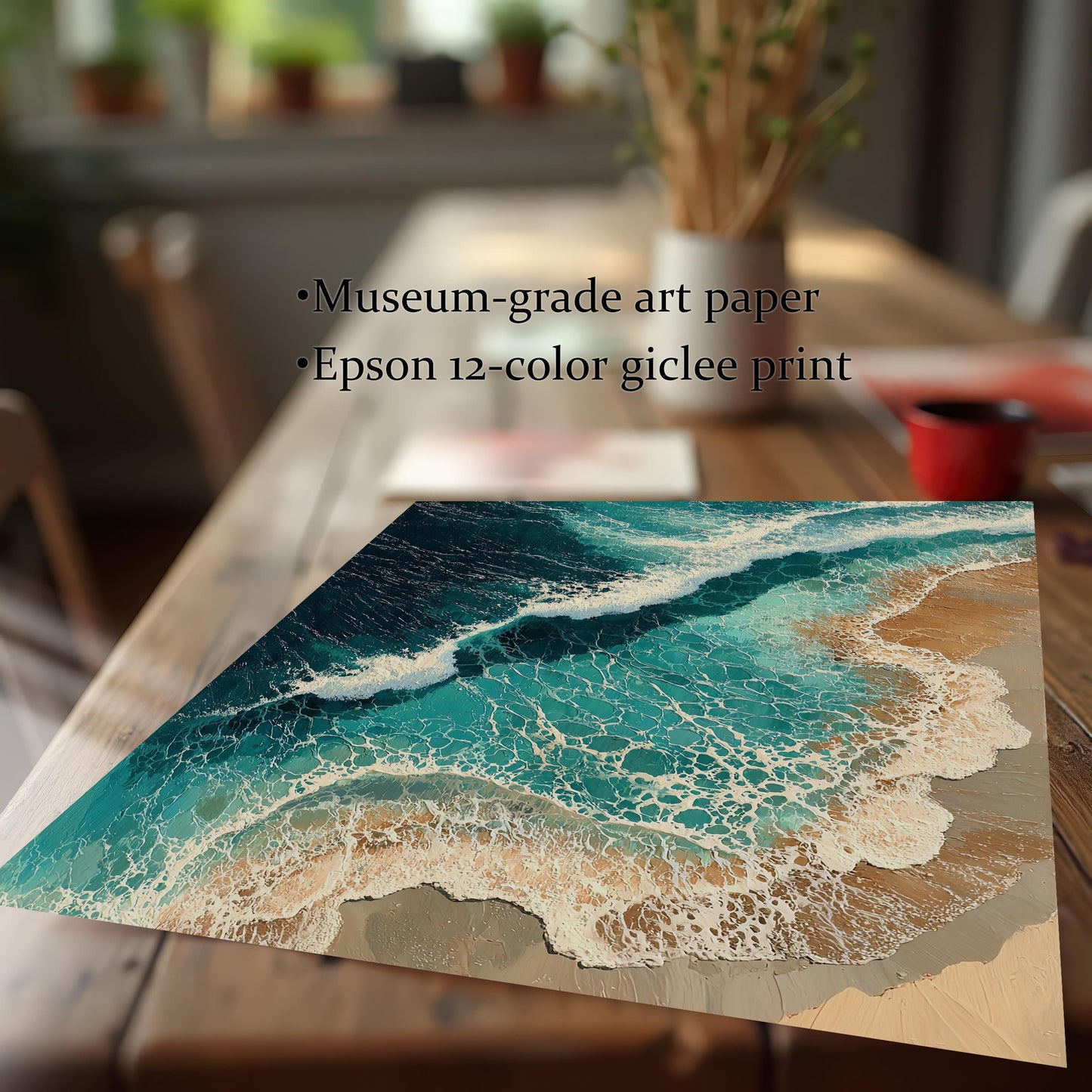 An unframed art print lies on a wooden table. The print is an aerial view of waves crashing on a beach. Text next to it lists its features: "Museum-grade art paper" and "Epson 12-color giclee print."