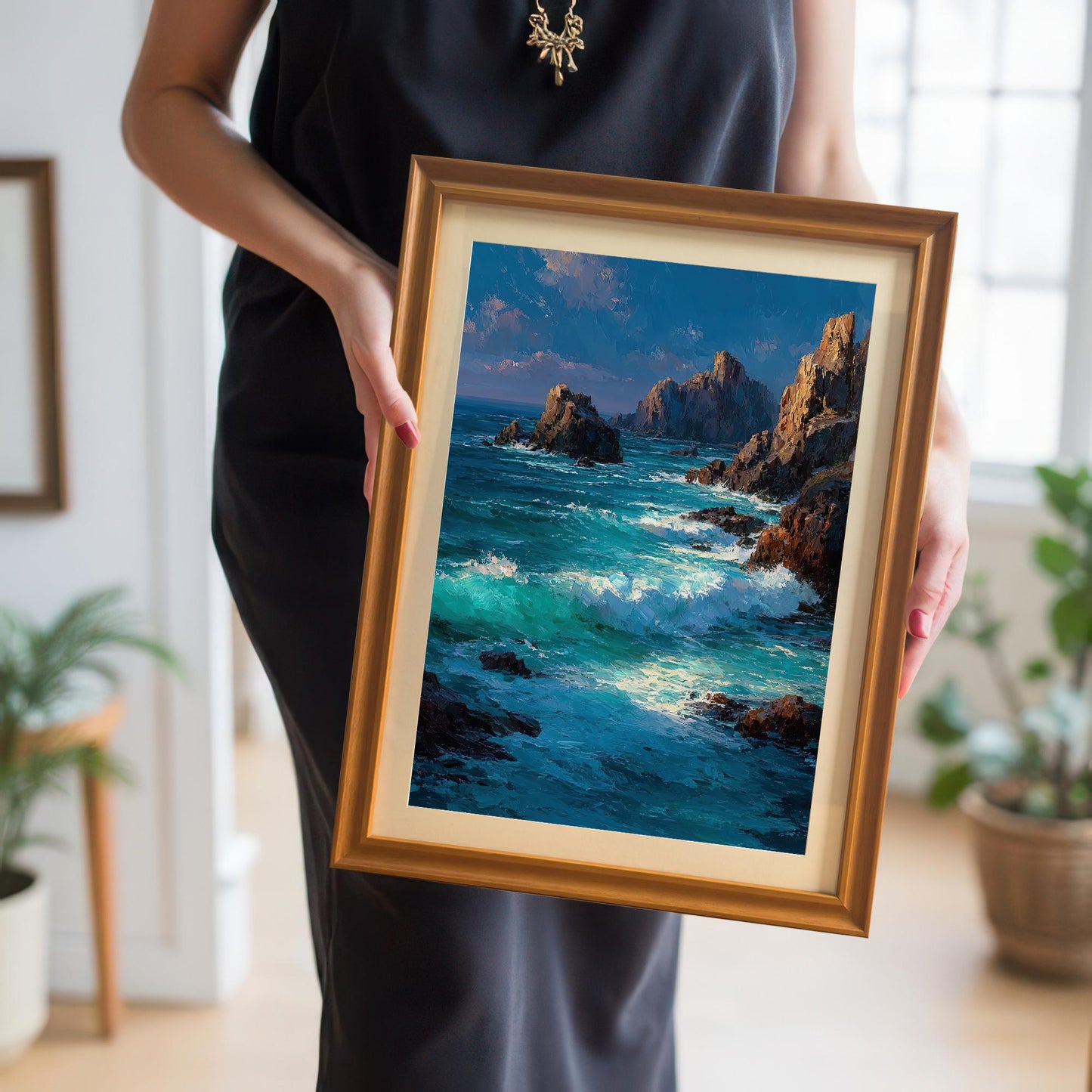 A person wearing a black dress holds a small, framed print of a seascape with an orange frame.