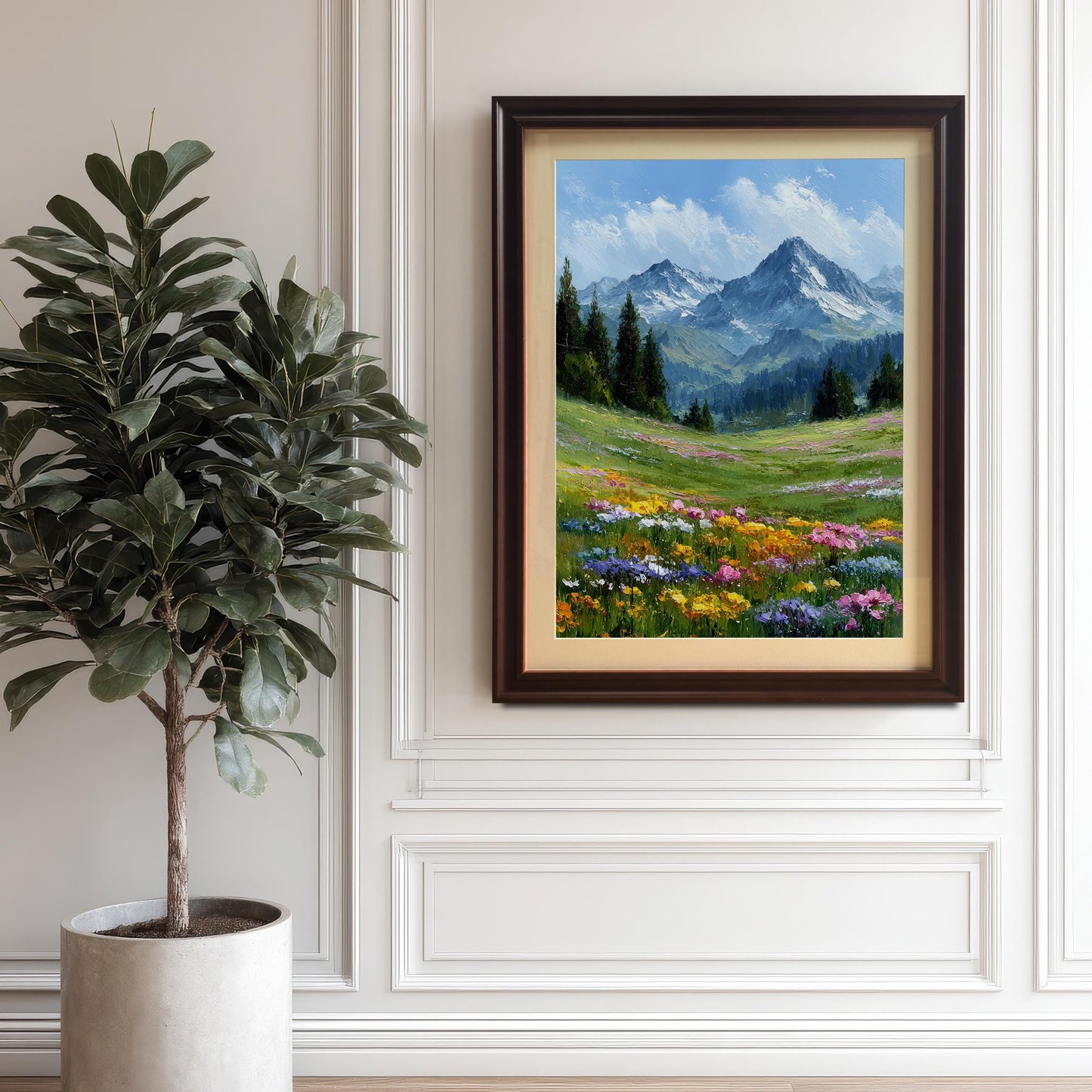 A framed painting of a mountain landscape with a field of colorful wildflowers hangs on a white paneled wall next to a large potted plant.