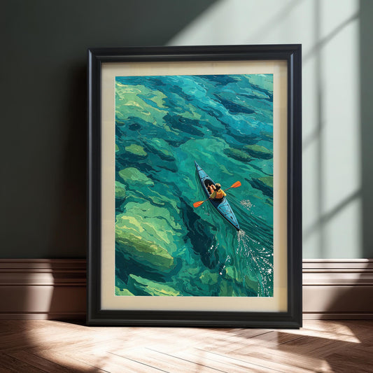 A black-framed art print of a person kayaking on clear turquoise water with a mount (mat) leans against a dark green paneled wall.