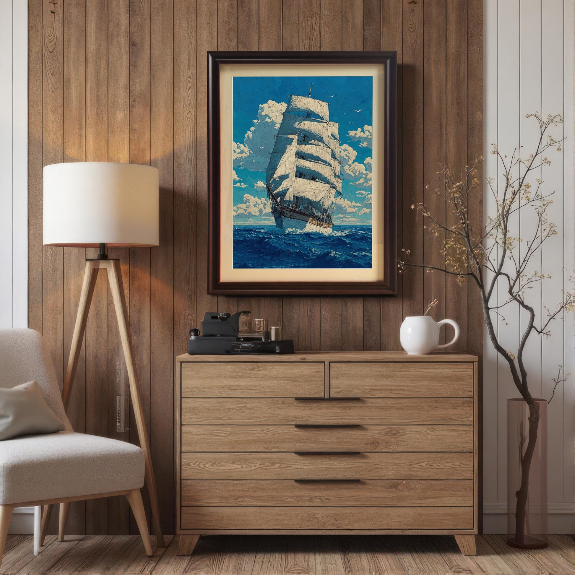 A framed painting with a metallic silver frame hangs on a wood-paneled wall above a light wooden dresser. The painting shows a tall ship sailing on a blue sea under a cloudy sky.
