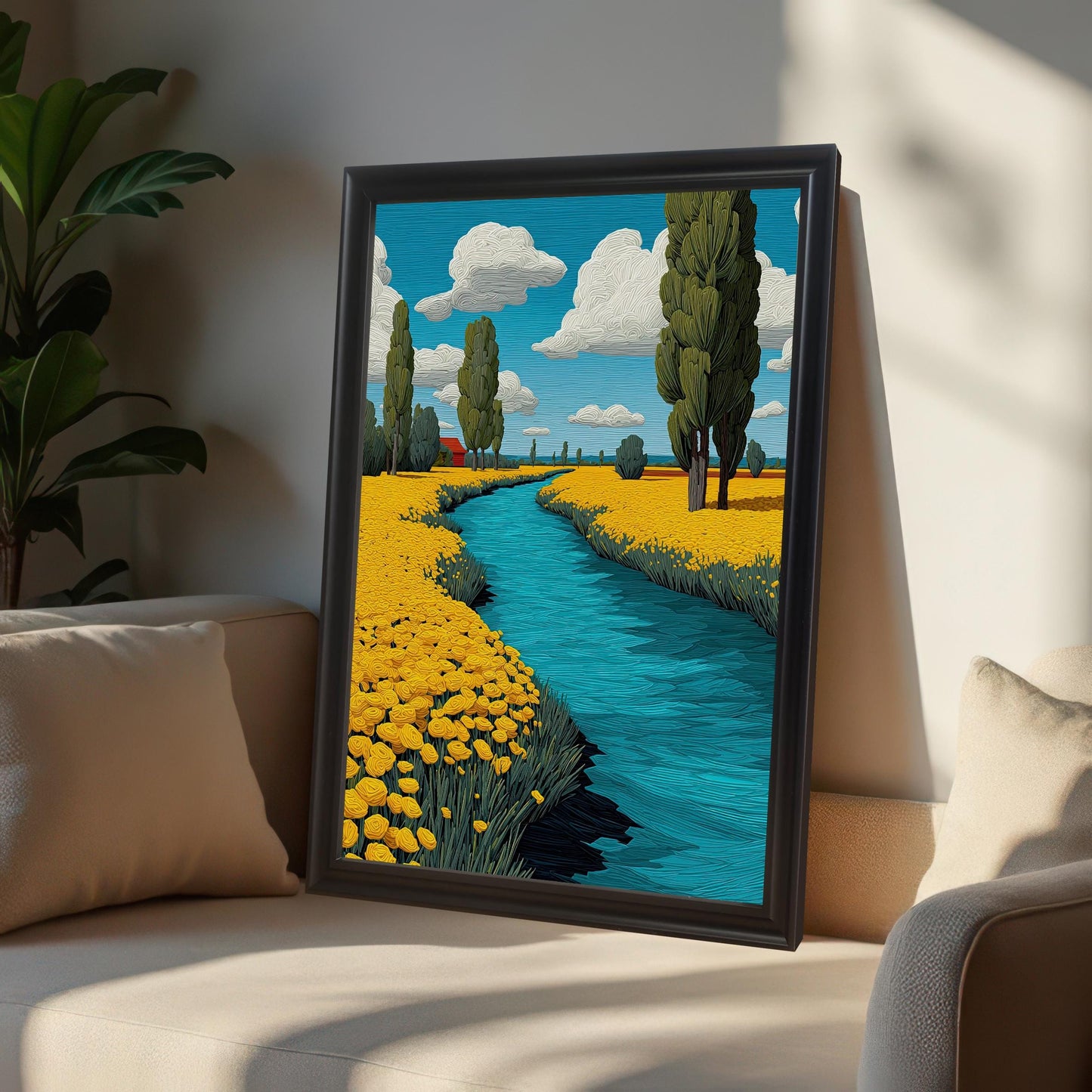 A painting of a river flowing through a field of yellow flowers. The painting, in a black frame, is leaning against a wall behind a beige armchair.