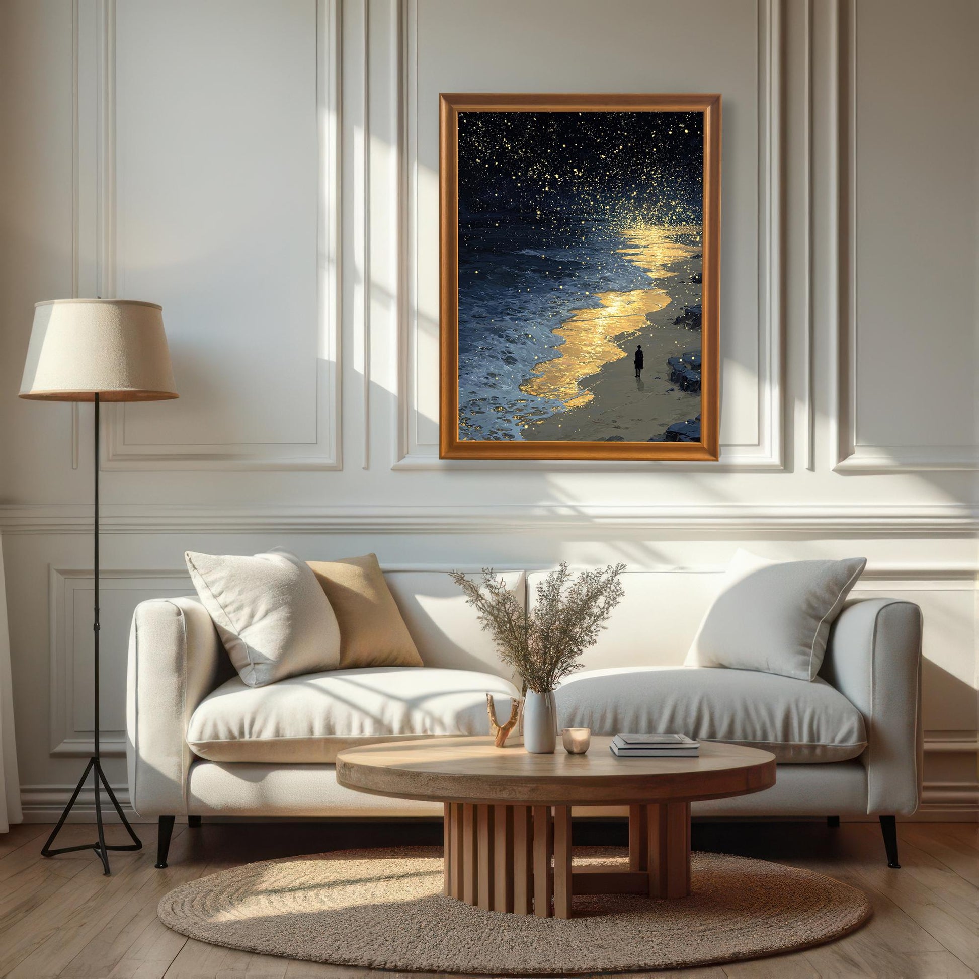 A framed painting of a starry night sky over a beach, hanging on a white paneled wall above a white couch.