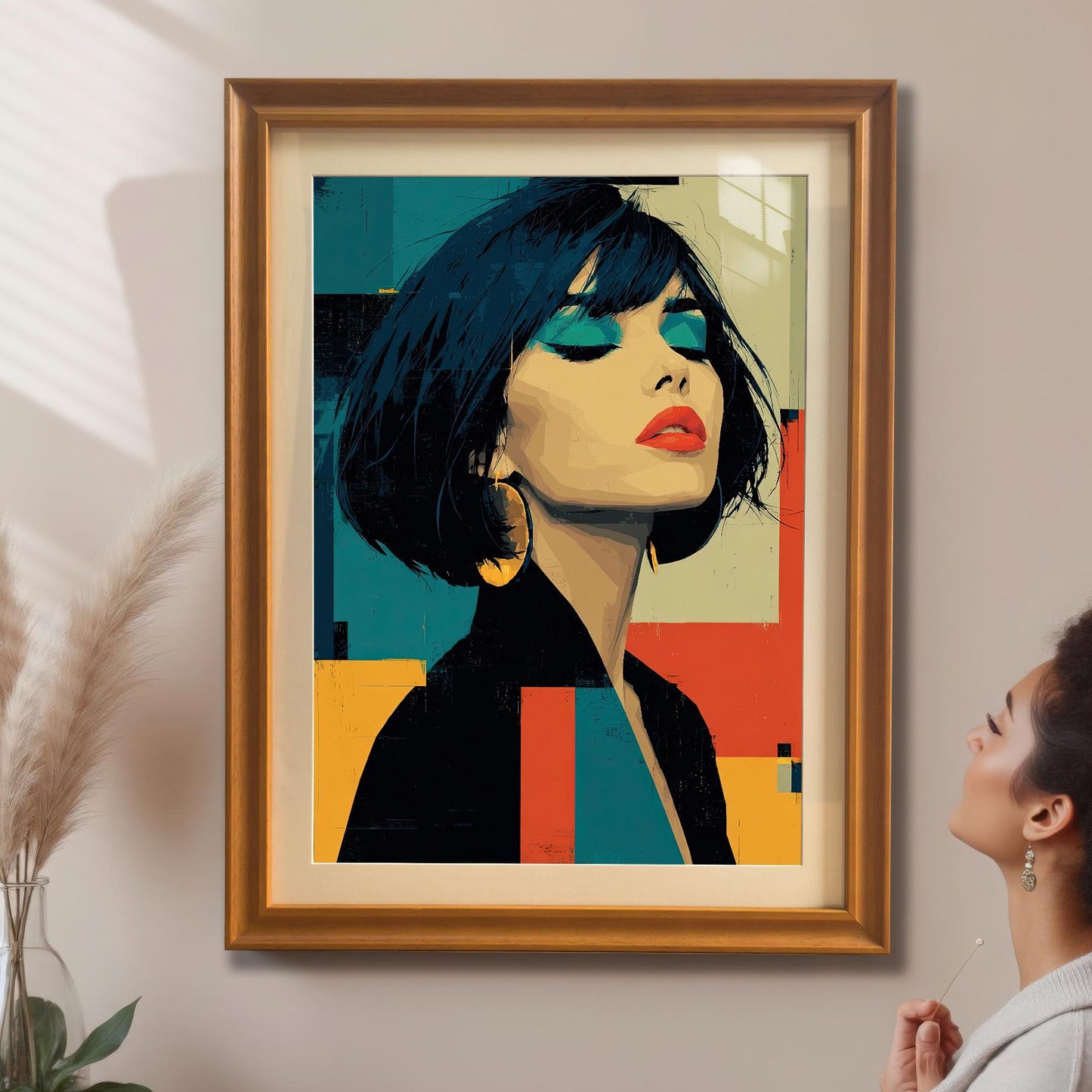 A modern pop art print of a woman in a black jacket with a gold frame is hanging on a beige wall. A woman with short, curly hair looks at the art from the right.