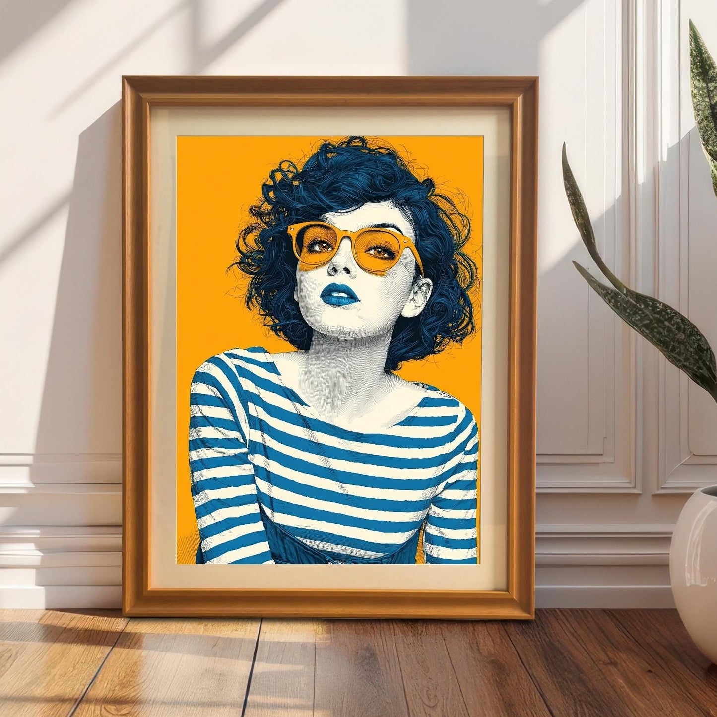 An orange-framed art print of a woman with orange sunglasses, leaning against a white wall with wainscoting. A snake plant in a white pot sits on the right.