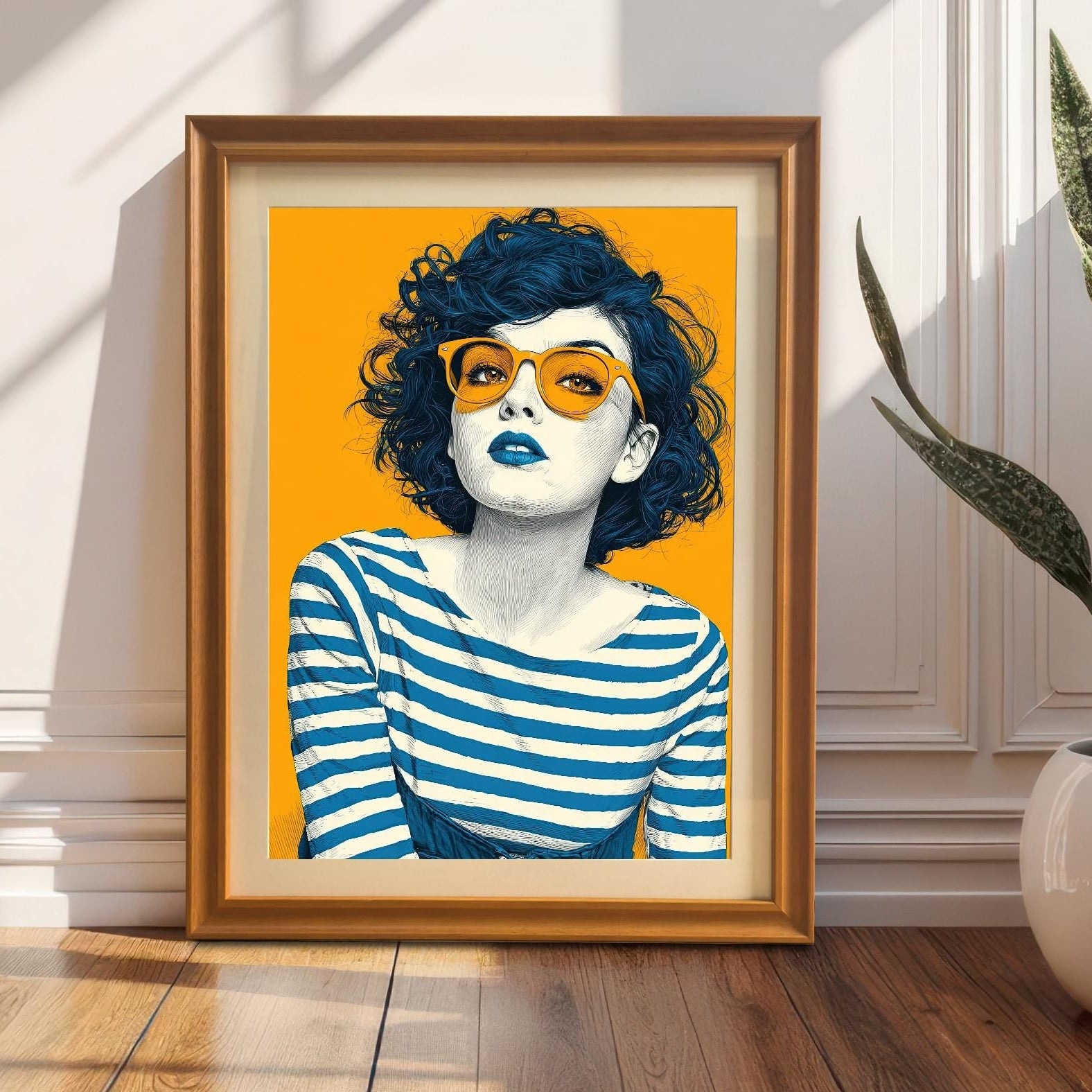 An orange-framed art print of a woman with orange sunglasses, leaning against a white wall with wainscoting. A snake plant in a white pot sits on the right.