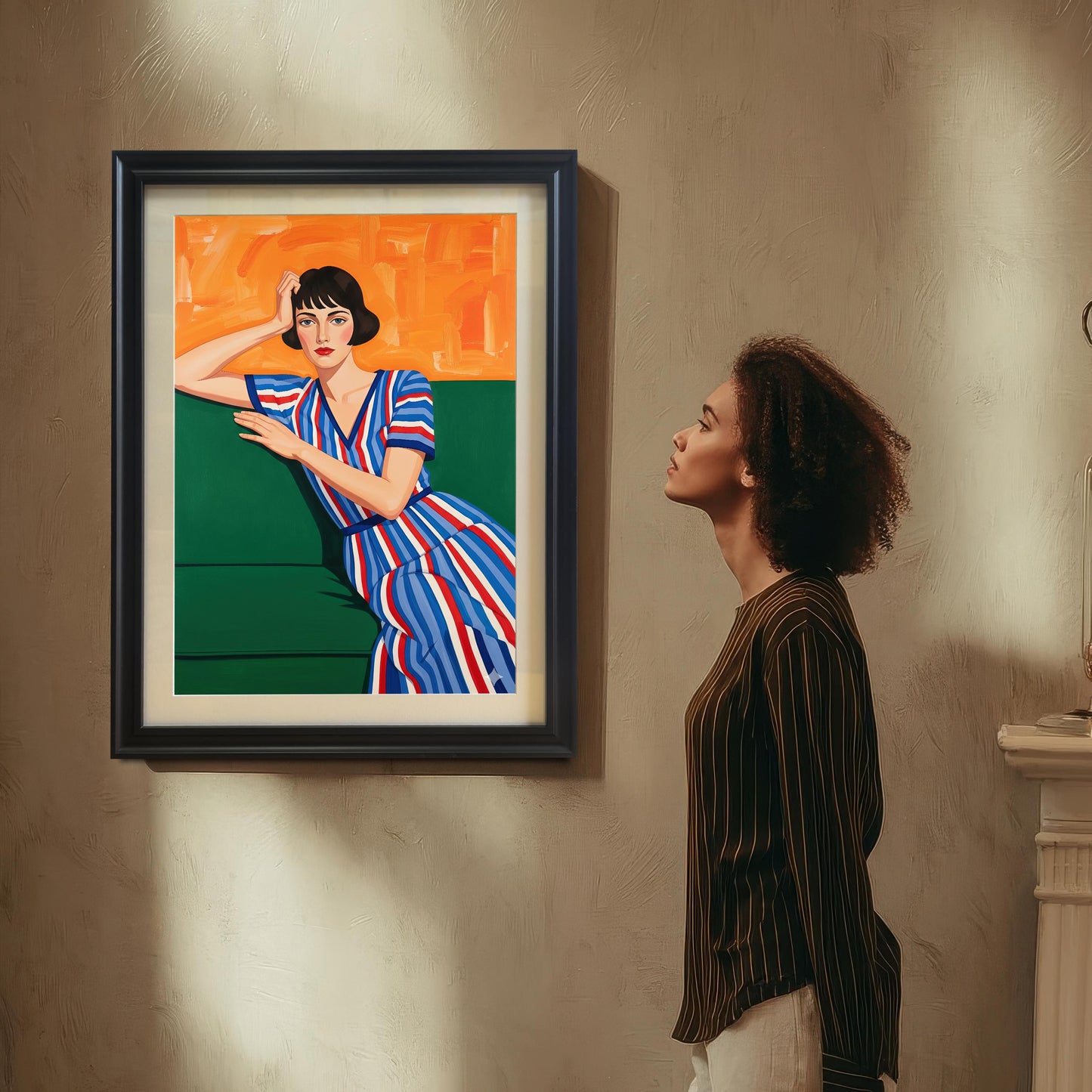 A woman with curly hair, wearing a striped shirt, looks up at a black-framed art print of a seated woman. The print hangs on a textured wall above a fireplace mantel.
