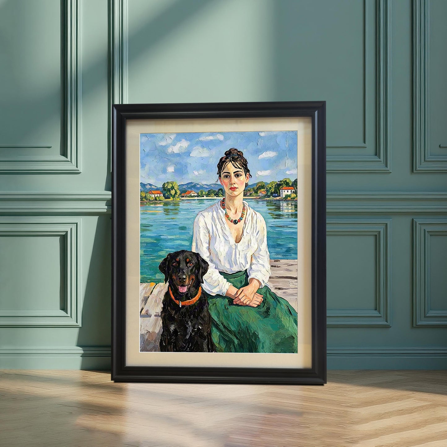 An oil painting of a woman and a black dog sitting on a wooden dock by a lake, displayed in a black frame on a wooden floor against a green wall.