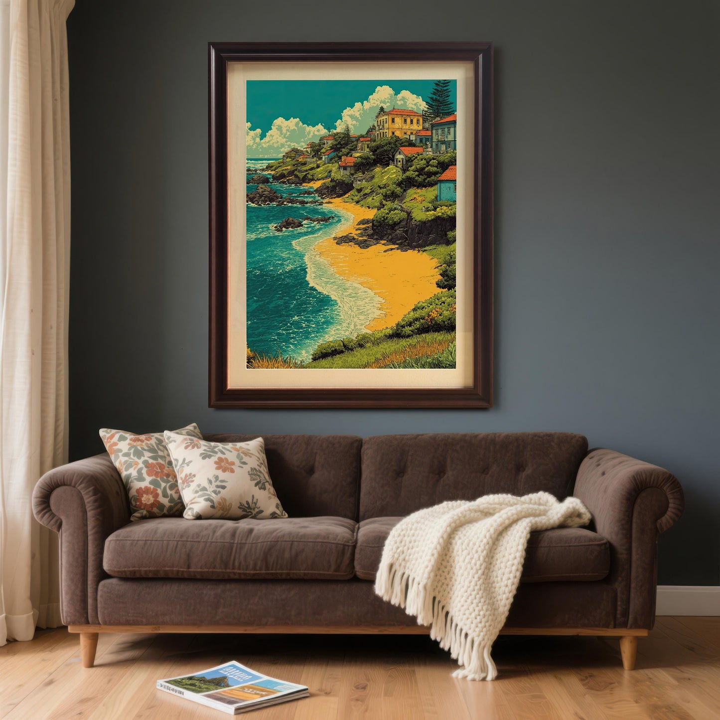 A painting of a village by a beach in a coffee brown frame is hanging on a dark gray wall above a brown couch.