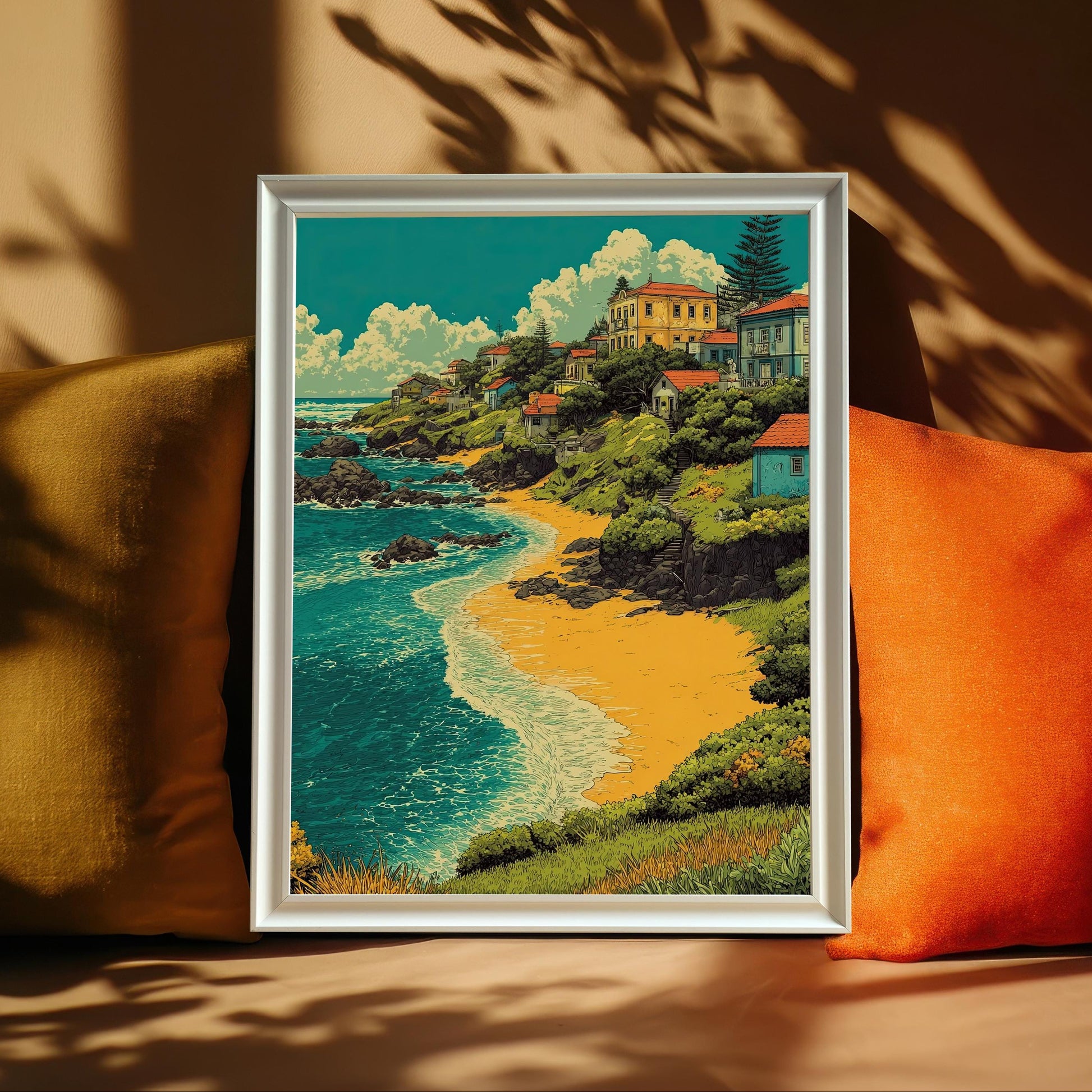 A painting of a village by a beach is leaning against yellow and orange pillows on a brown couch. The artwork is in a white frame.