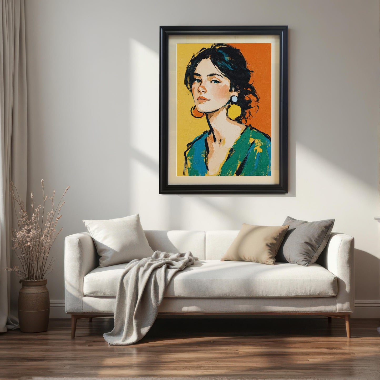 A framed art print of a woman with a serious expression and large earrings hangs on a white wall above a beige couch with pillows. The frame is black and has a mount.