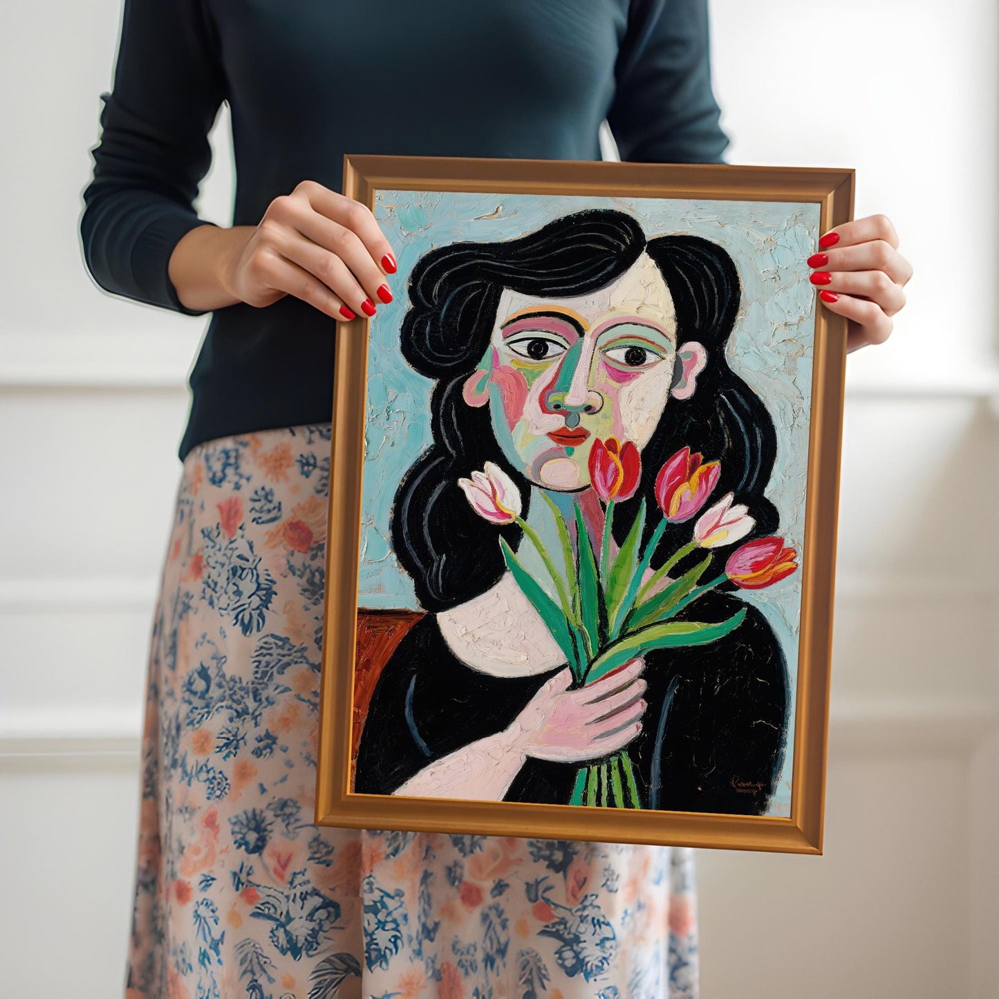 A person in a floral skirt holds up a framed art print of a woman with tulips. The frame is orange.