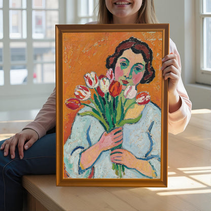 A woman holds up a framed art print of a woman with tulips. The frame is orange.