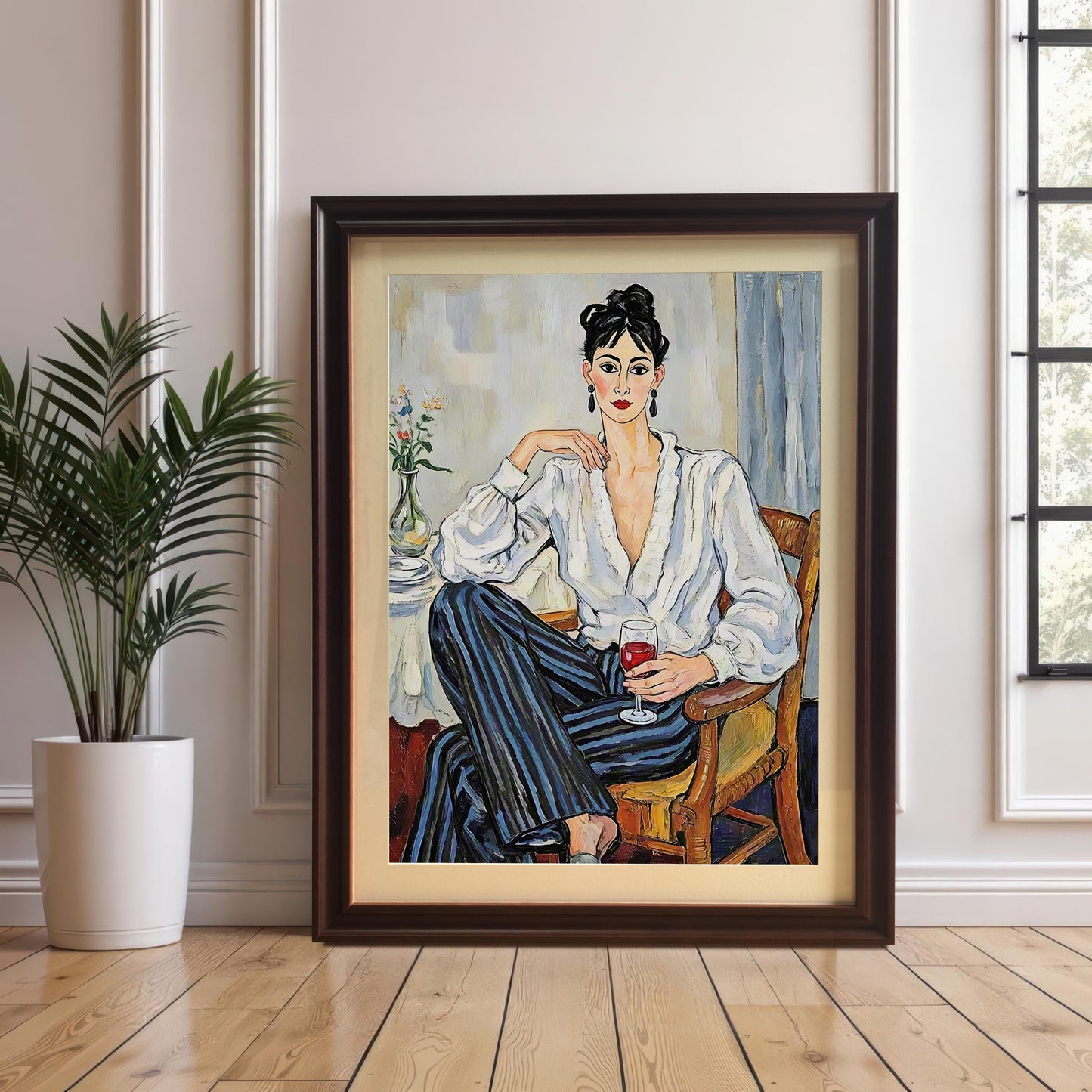 A framed art print of a woman in a white blouse and striped pants leaning against a wall next to a houseplant. The frame is a dark brown or coffee color with a mount.