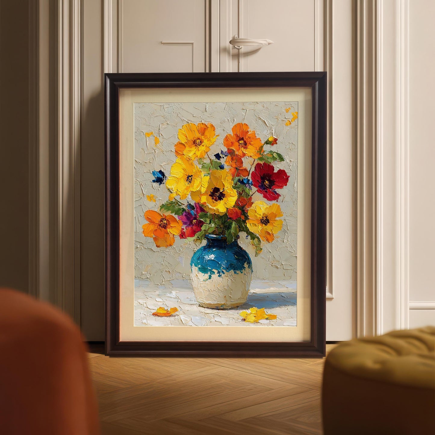 A coffee-colored framed painting of a vase with flowers is propped up on a wooden floor in front of a closet door.