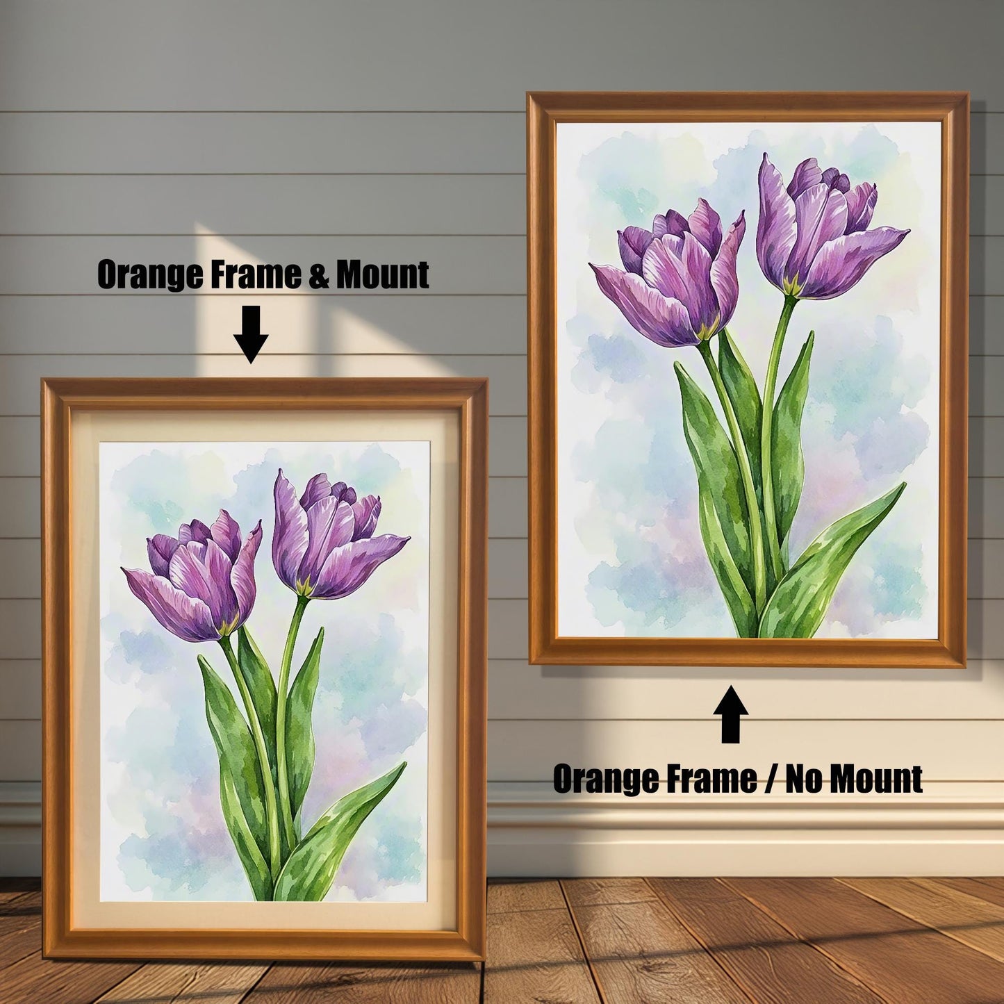 Two framed art prints of purple tulips on a wooden floor. The print on the left is in an orange frame with a mount, and the one on the right is in an orange frame without a mount.